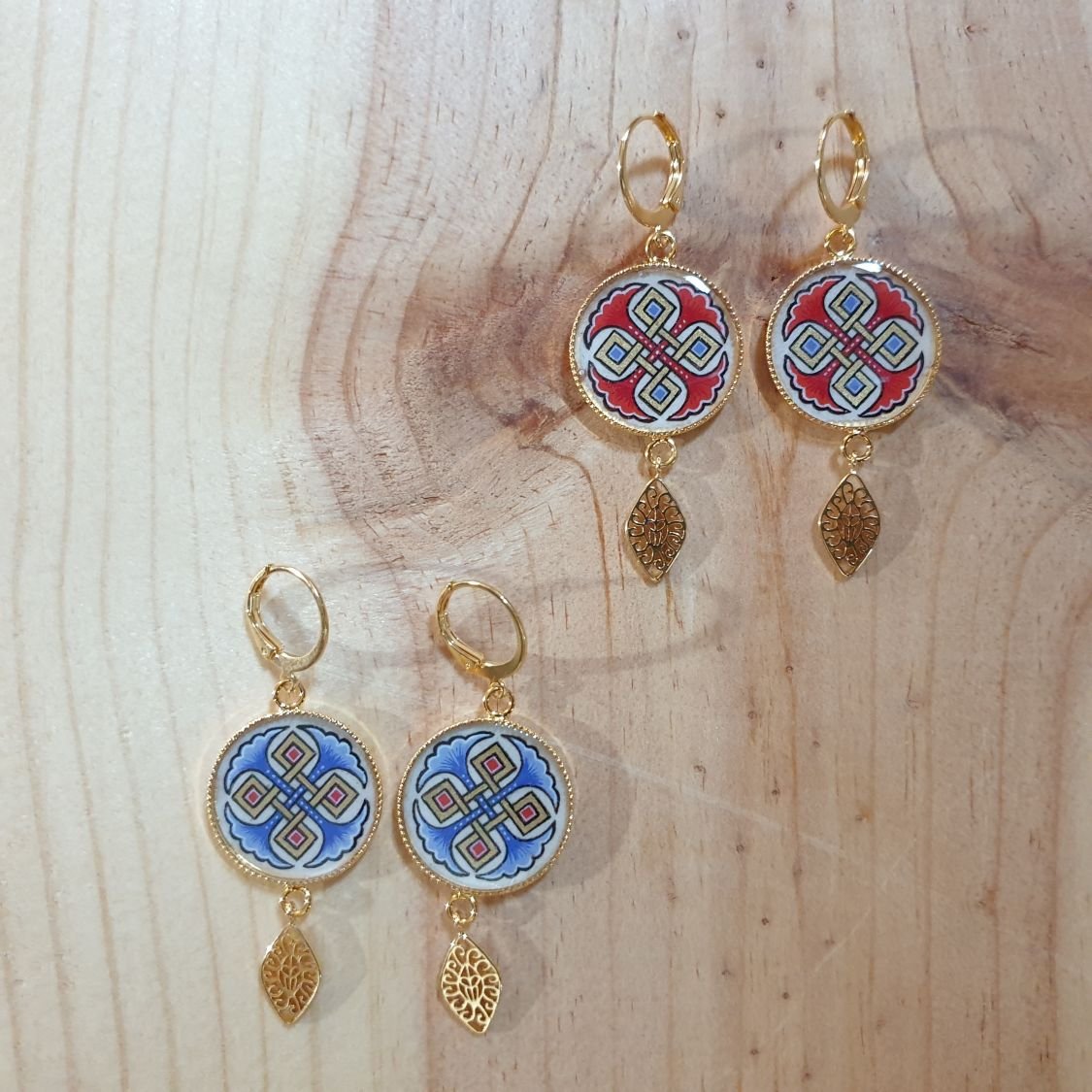 Rode of blauwe palmetten en gouden hanger oorbellen.