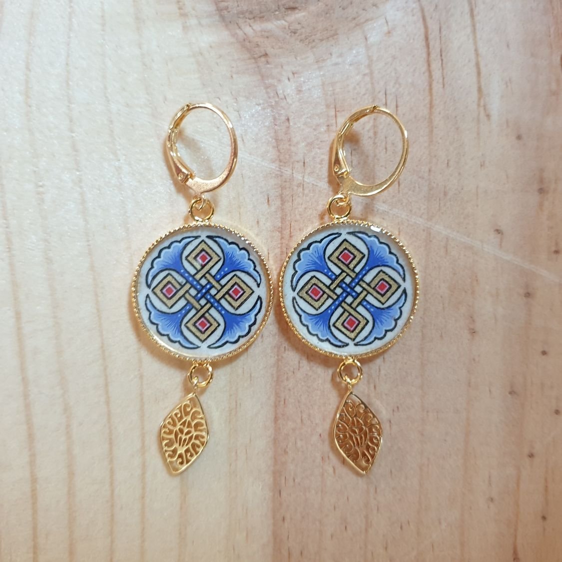 Rode of blauwe palmetten en gouden hanger oorbellen.