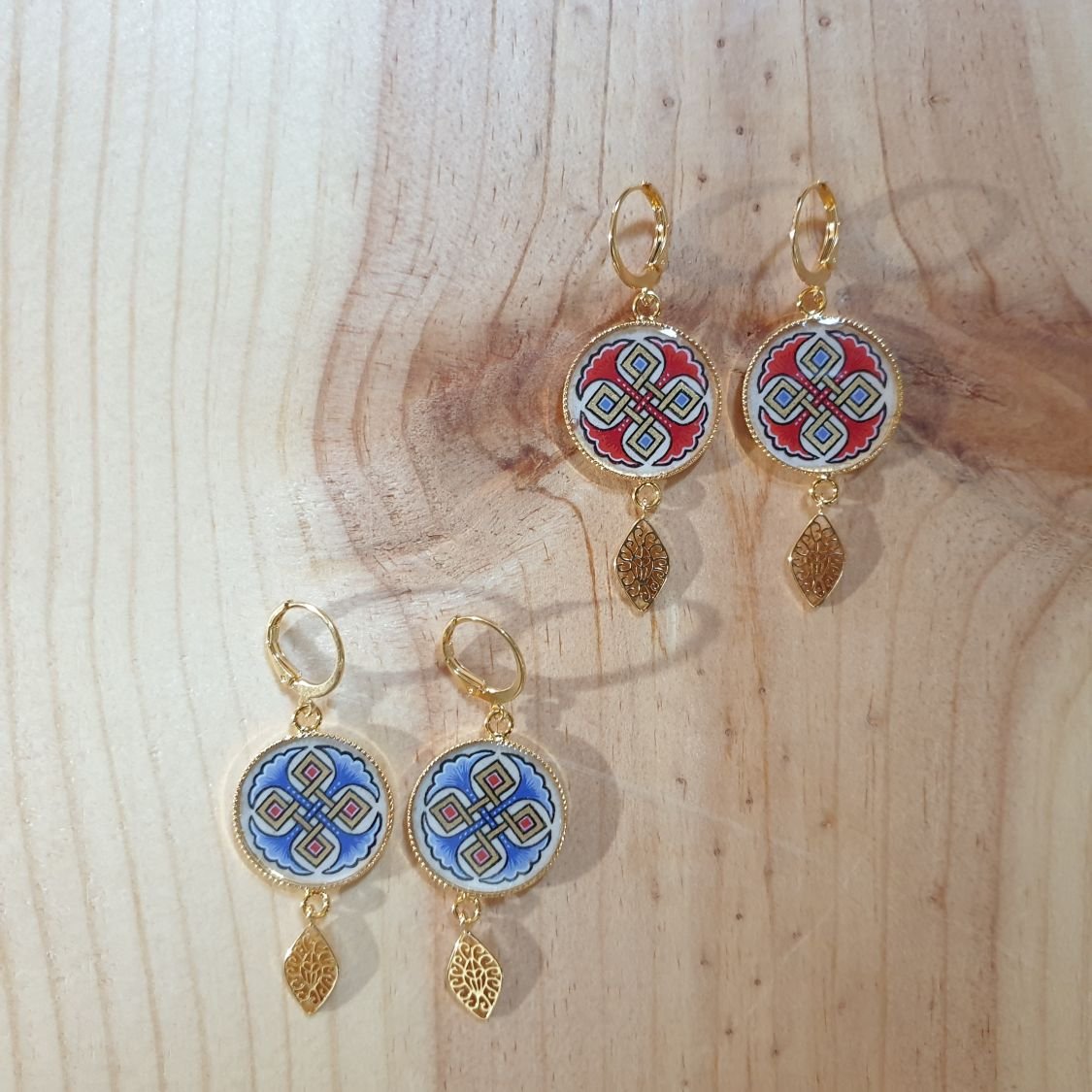 Rode of blauwe palmetten en gouden hanger oorbellen.