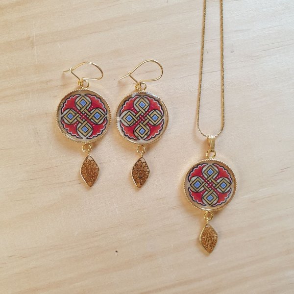 Halshanger verlicht met blauwe palmetten, goud en rood vlechtwerk aan gouden ketting