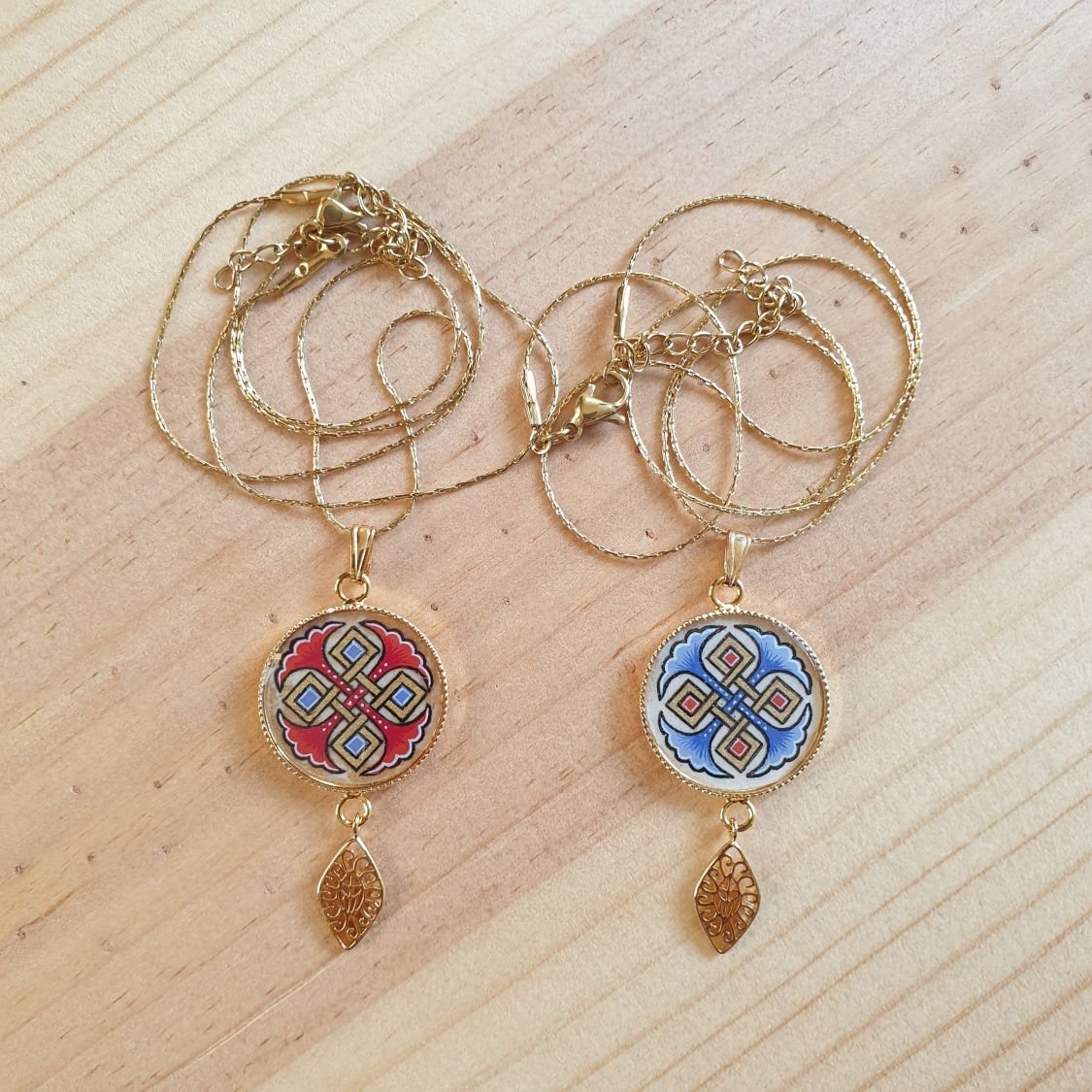 Halshanger verlicht met blauwe palmetten, goud en rood vlechtwerk aan gouden ketting