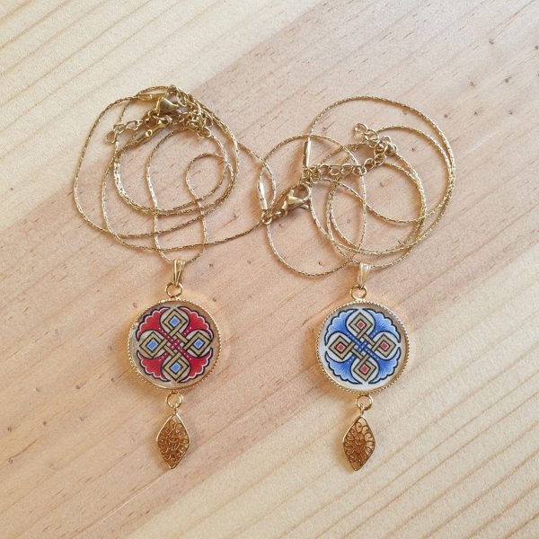 Halshanger verlicht met blauwe palmetten, goud en rood vlechtwerk aan gouden ketting