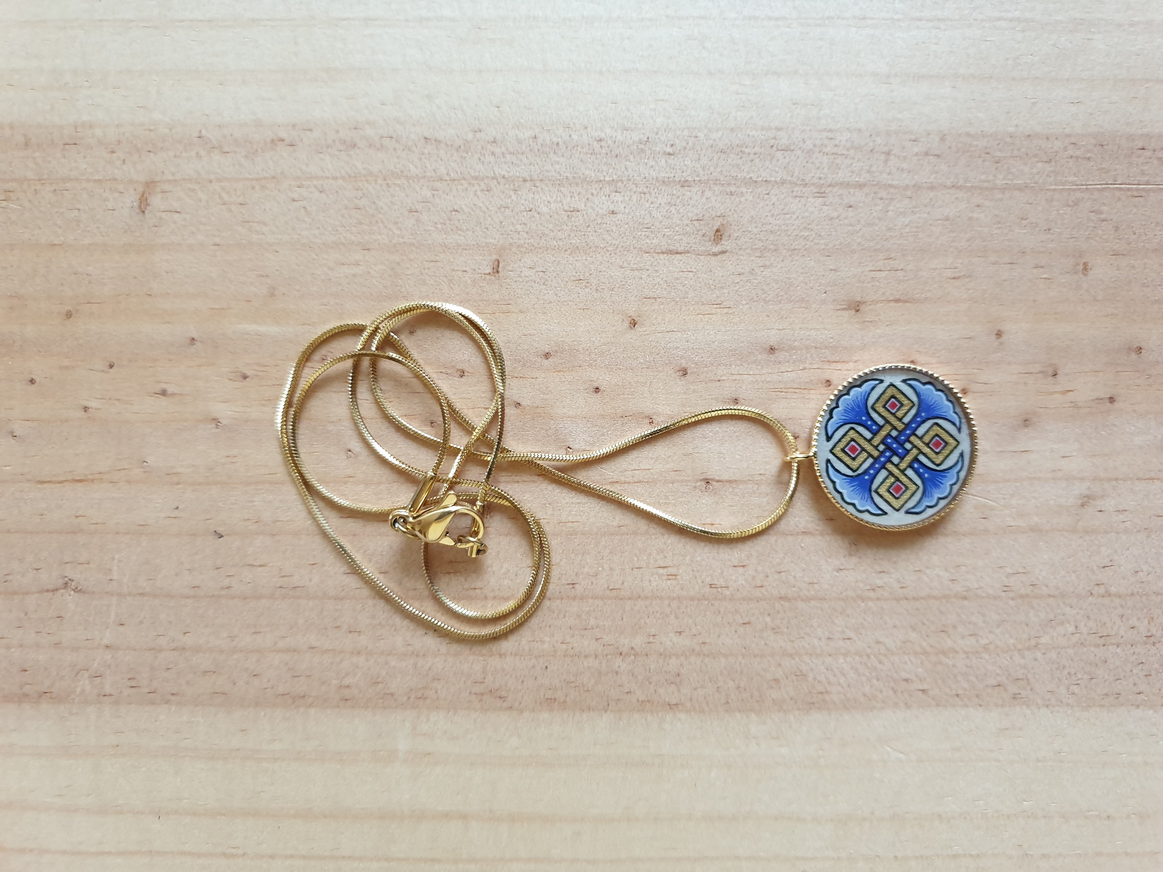 Hanger collier met blauwe palmetten, goud en rood vlechtwerk aan gouden ketting