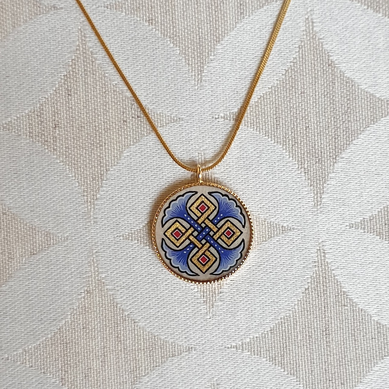 Hanger collier met blauwe palmetten, goud en rood vlechtwerk aan gouden ketting