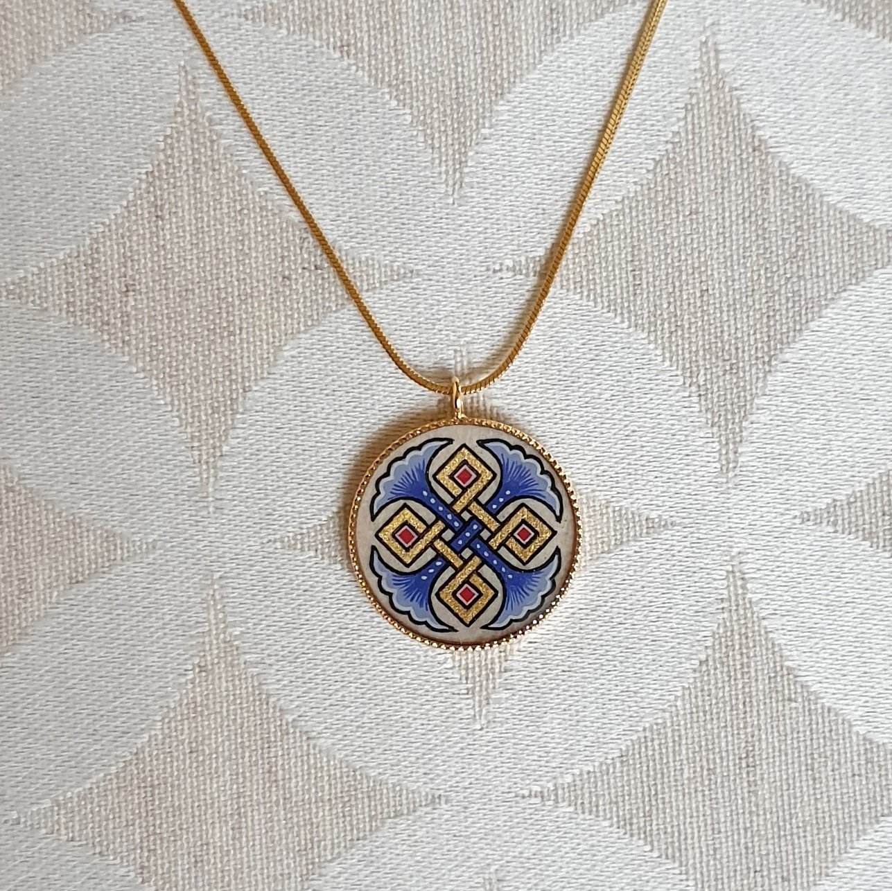 Hanger collier met blauwe palmetten, goud en rood vlechtwerk aan gouden ketting