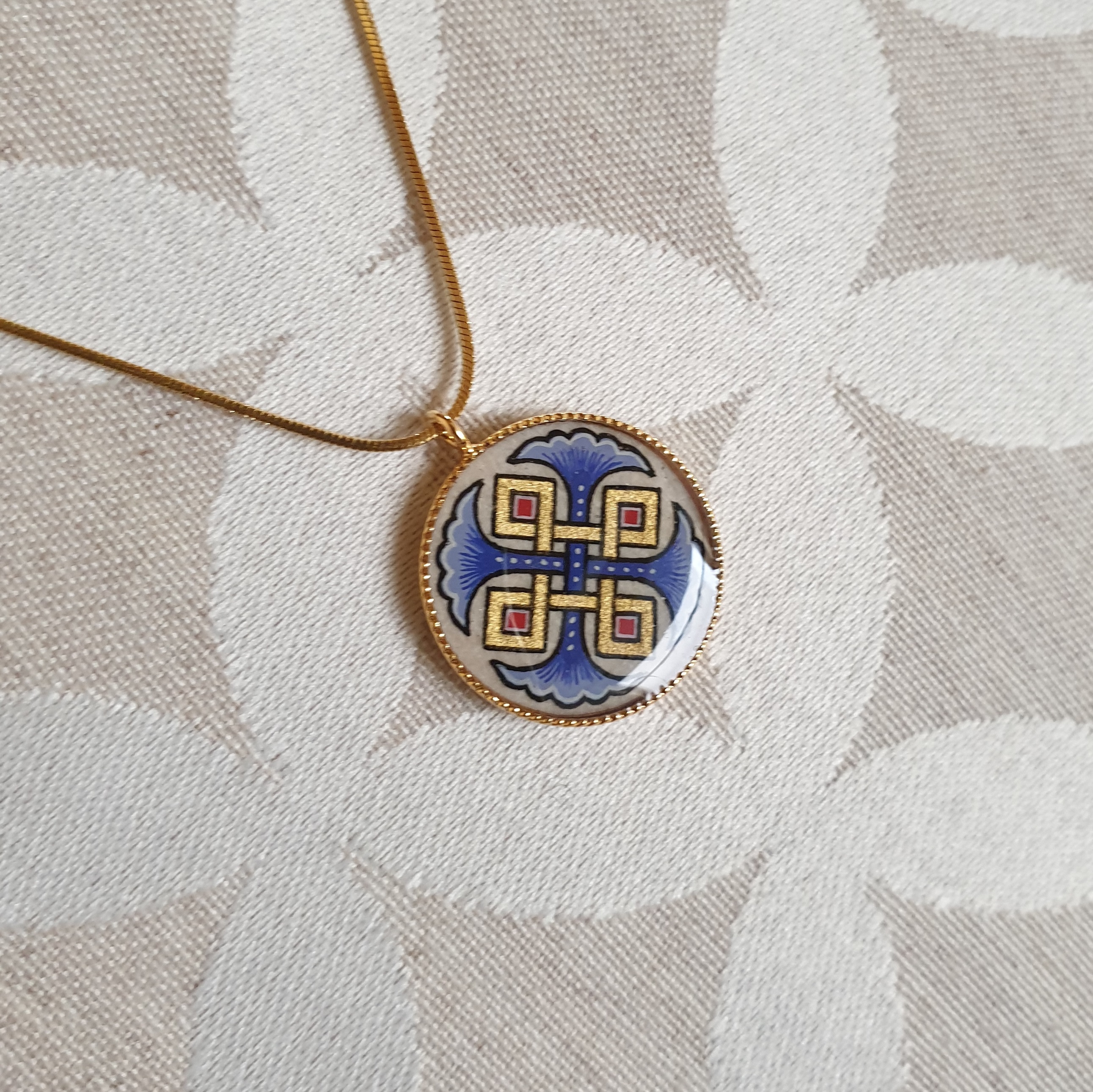 Hanger collier met blauwe palmetten, goud en rood vlechtwerk aan gouden ketting