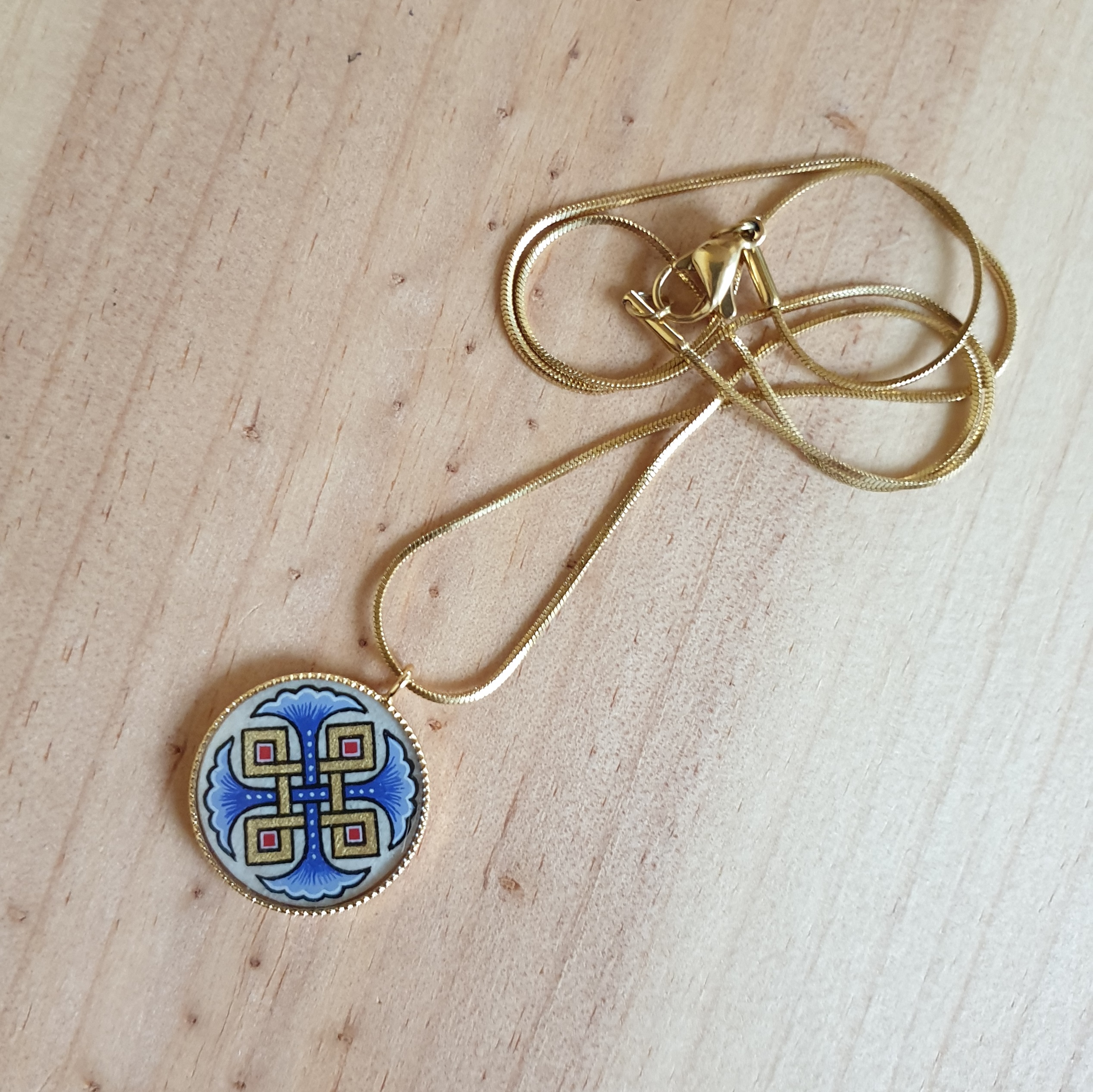 Hanger collier met blauwe palmetten, goud en rood vlechtwerk aan gouden ketting