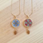 Halshanger verlicht met blauwe palmetten, goud en rood vlechtwerk aan gouden ketting